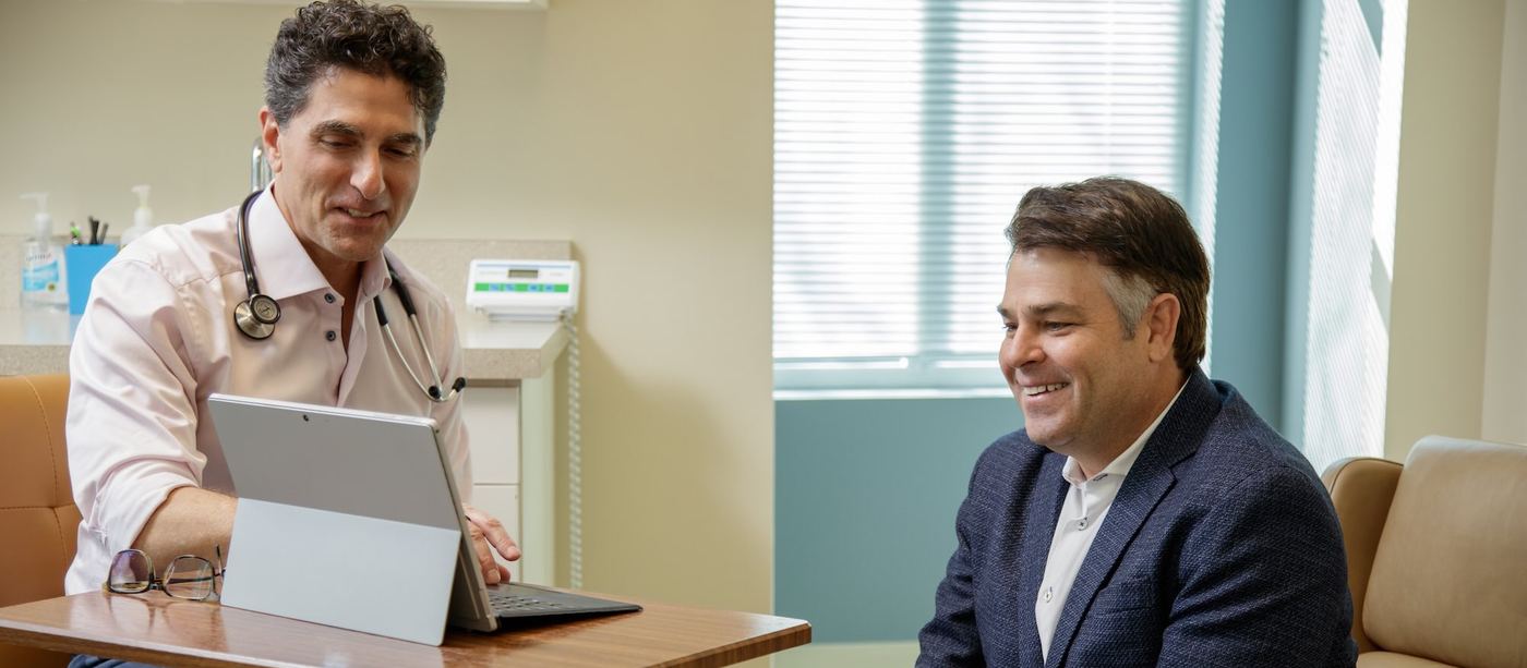 Dr. Carlos Jorge reviewing a plan on a tablet with a smiling client in a Companion Health exam room